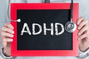 a doctor is holding a blackboard with the word adhd written on it .