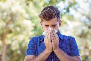 a man is blowing his nose into a napkin with allergies