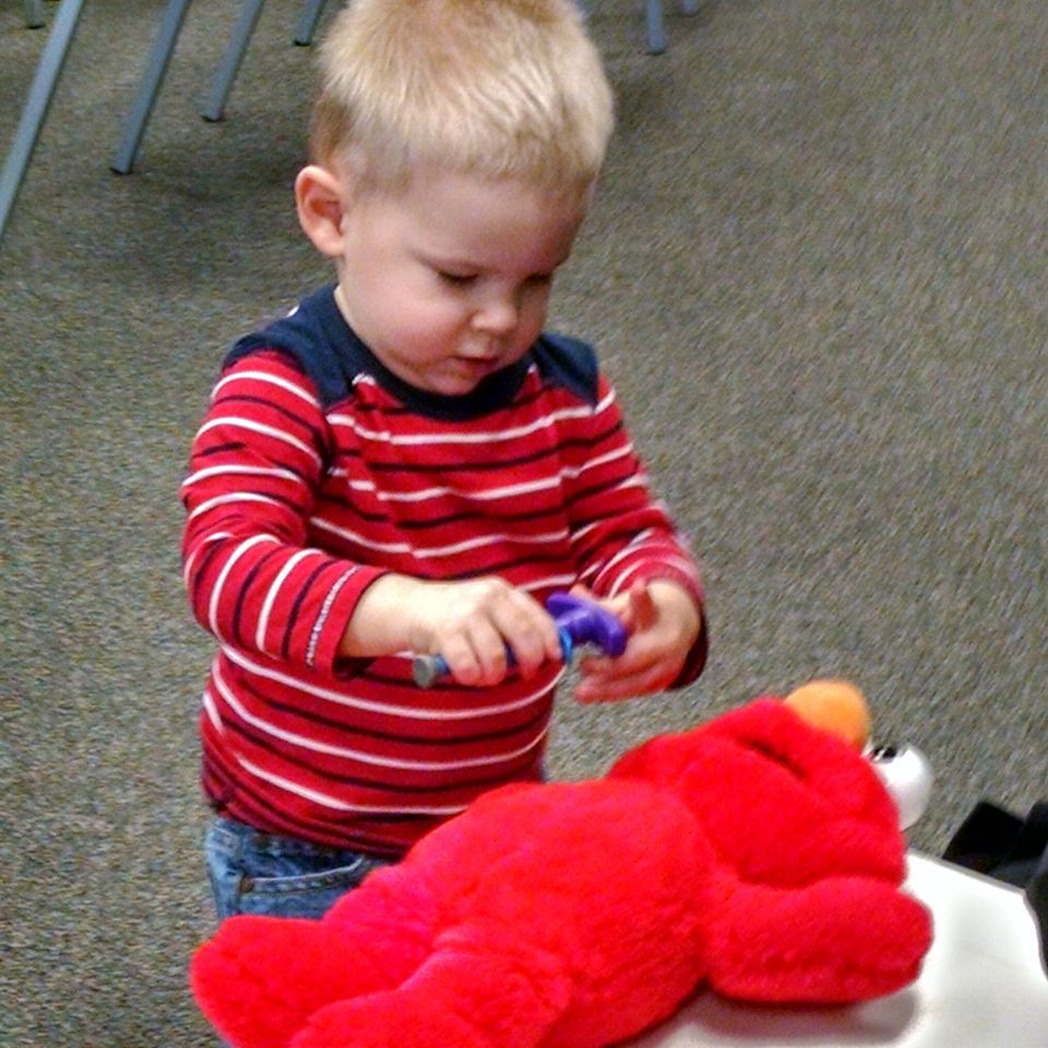 a young boy is playing with a stuffed red elmo at Chiropractor office