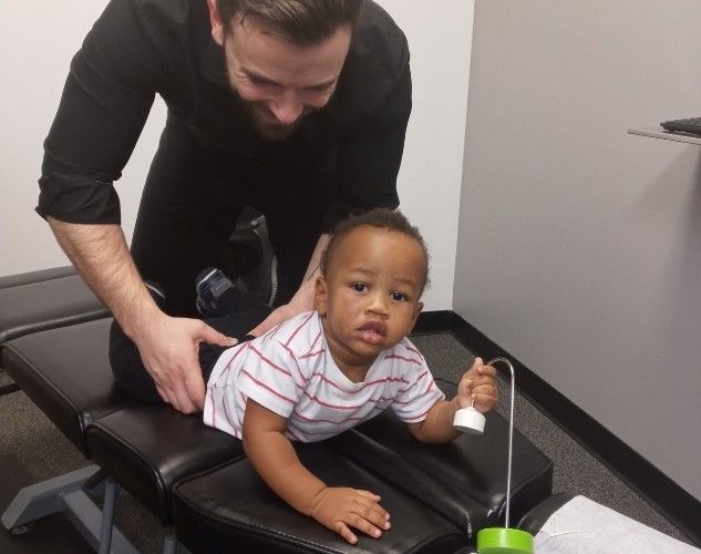 a little boy is laying on a table while a Chiropractor Adjusts him