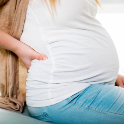 a pregnant woman is sitting down with her hand on her belly, back pain