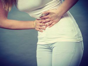 a woman is holding her stomach in pain with digestive problems