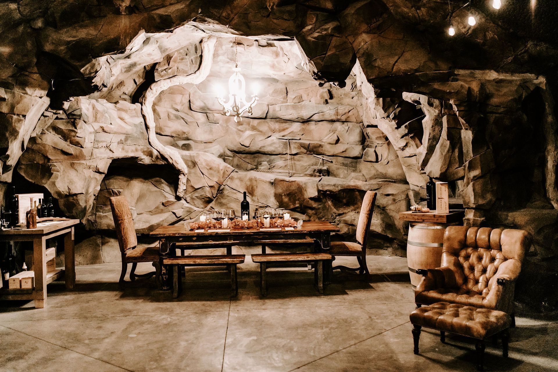 A dining room with a table and chairs in front of a rock wall.