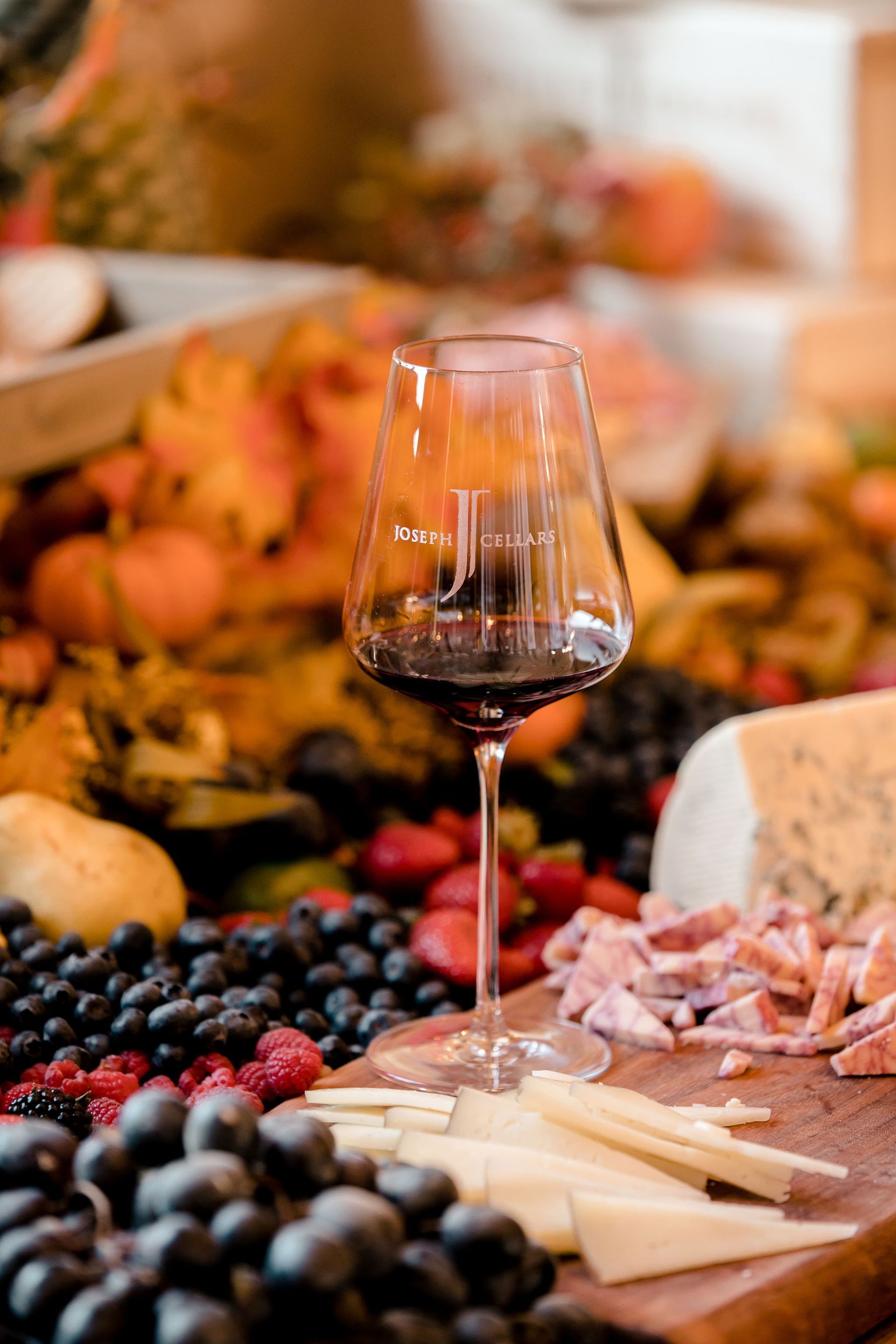 A glass of red wine is sitting on top of a wooden cutting board.
