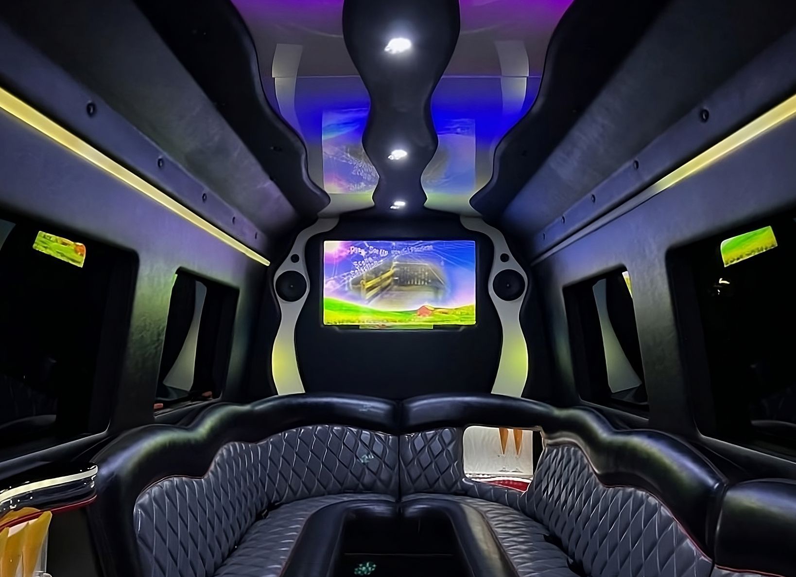 The inside of a limousine with a flat screen tv on the ceiling.