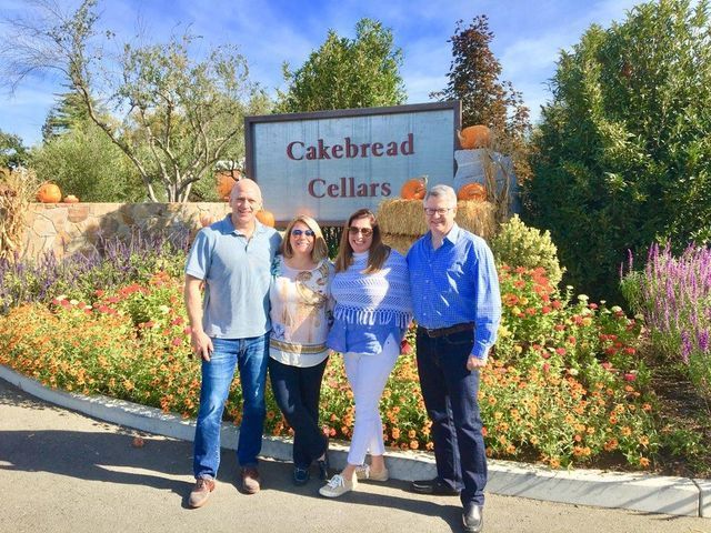 A group of people standing in front of a sign that says cakebread cellars
