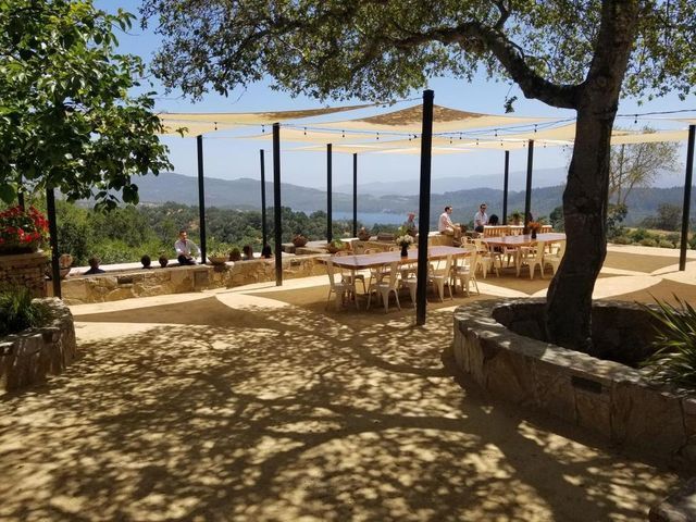 A patio with tables and chairs under a canopy with a view of the mountains.