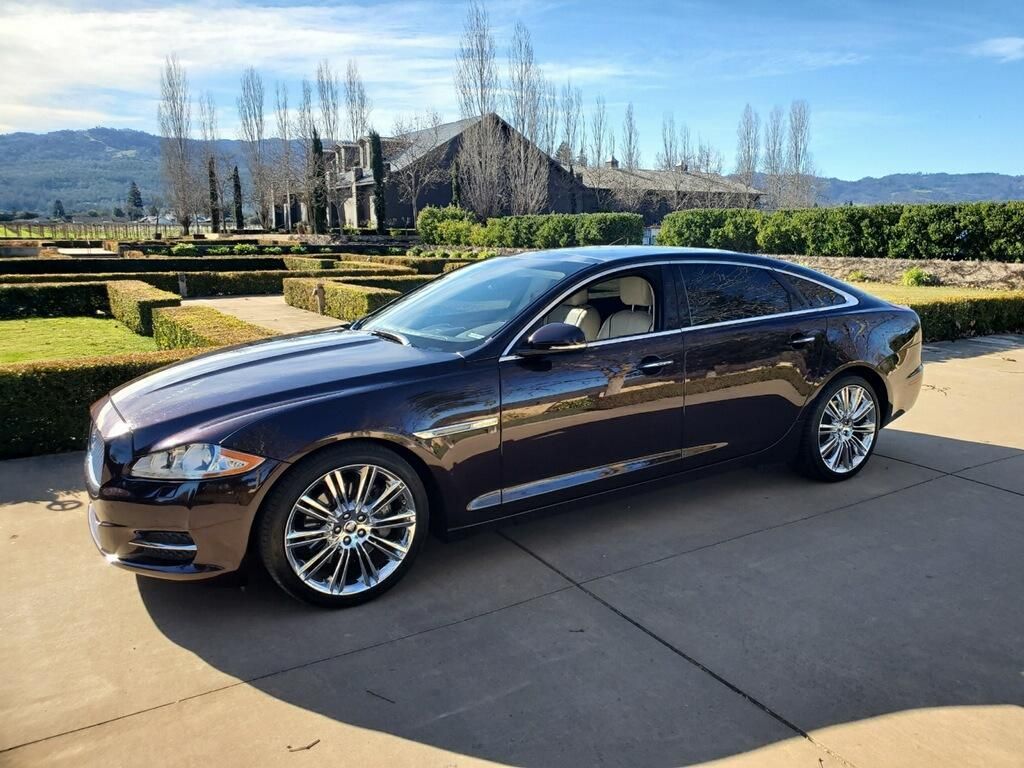 A black car is parked in a driveway in front of a house.