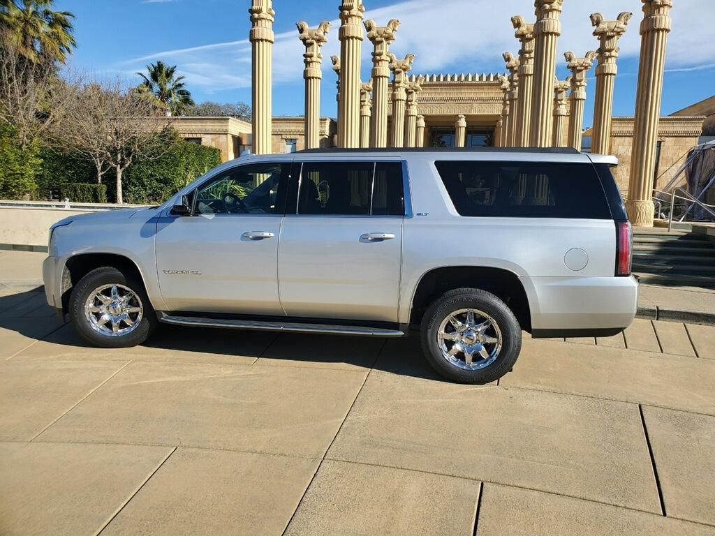A silver suv is parked in front of a building with columns.