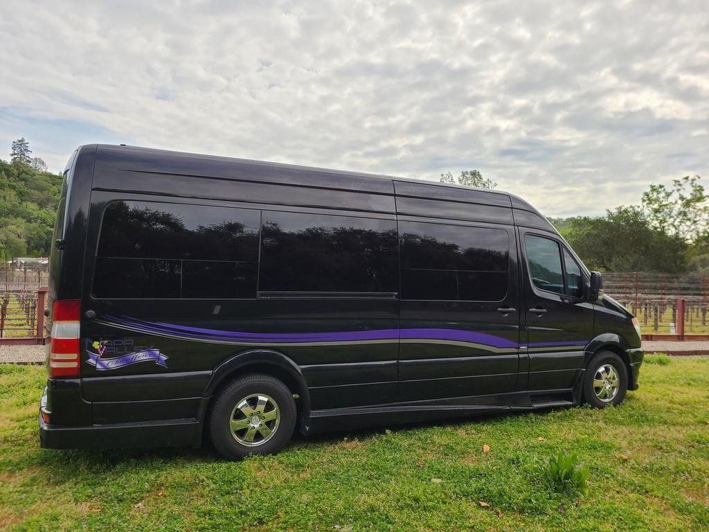 A black van is parked in a grassy field.