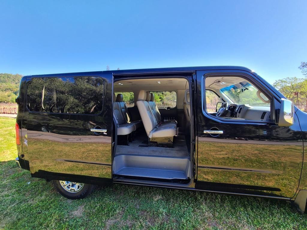 A black van with the doors open is parked in the grass.