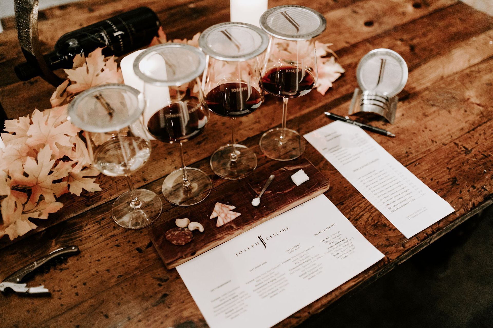 A wooden table topped with wine glasses and a bottle of wine.