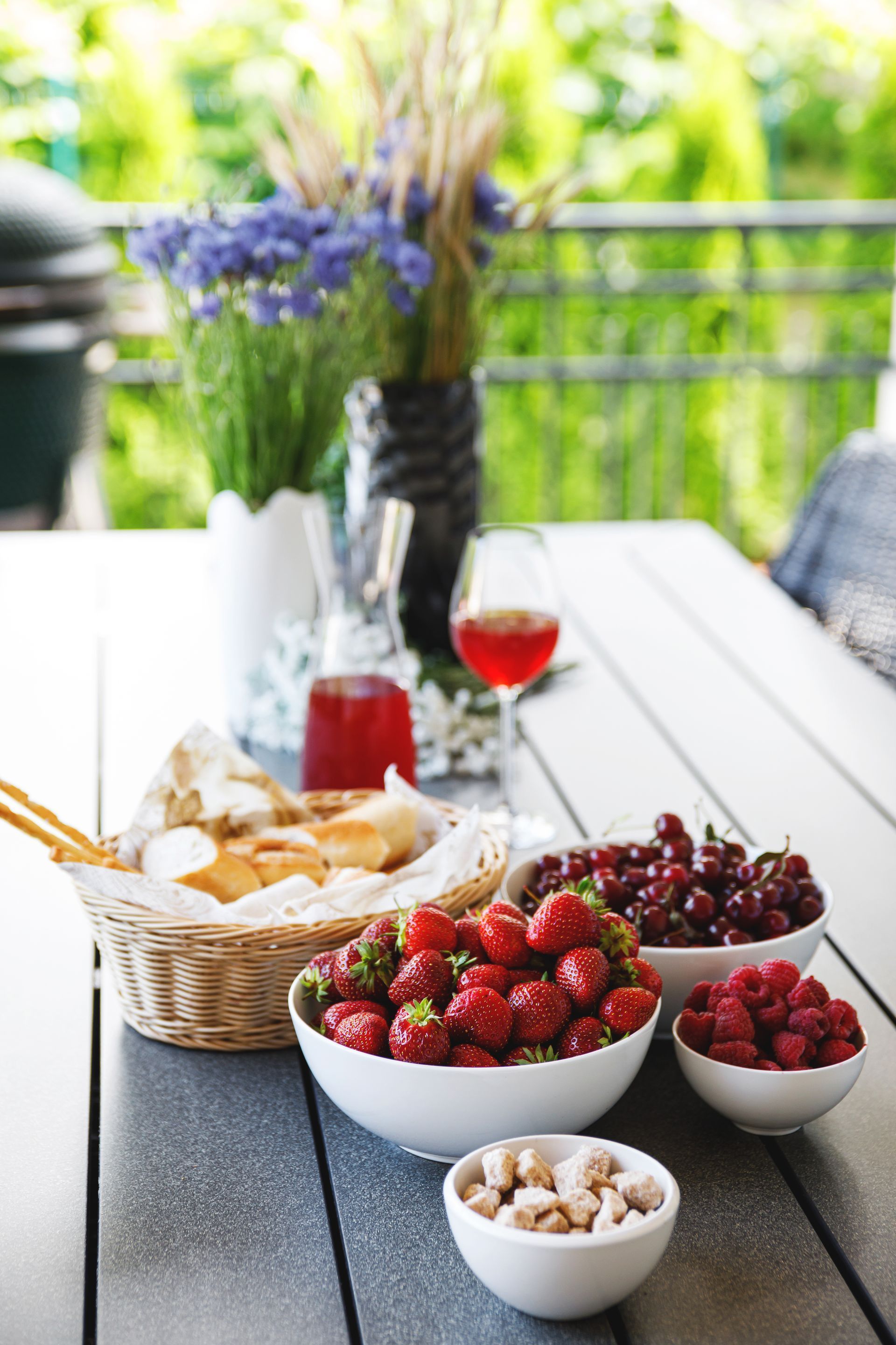 A table topped with bowls of fruit and nuts and a glass of wine.