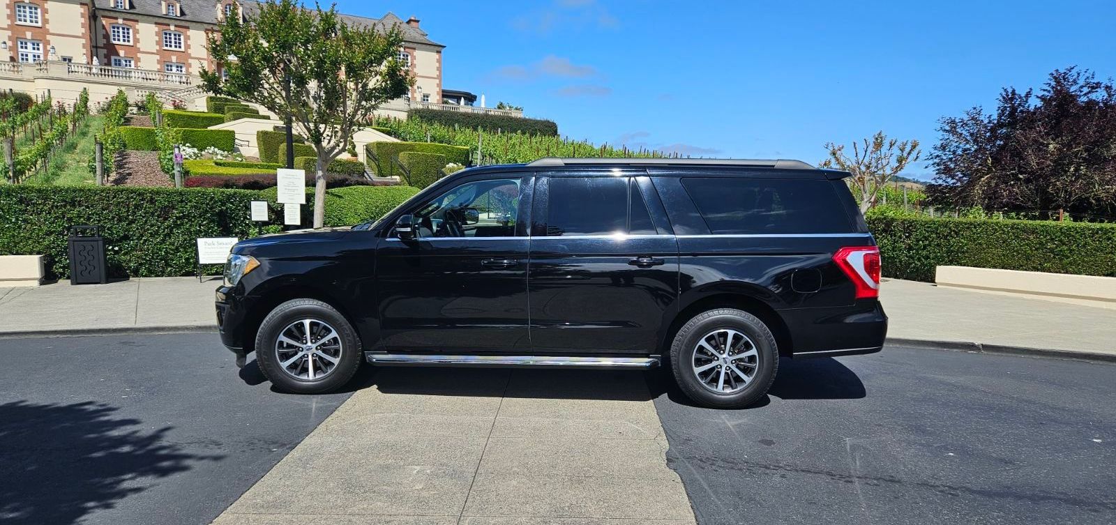 A black suv is parked on the side of the road in a parking lot.