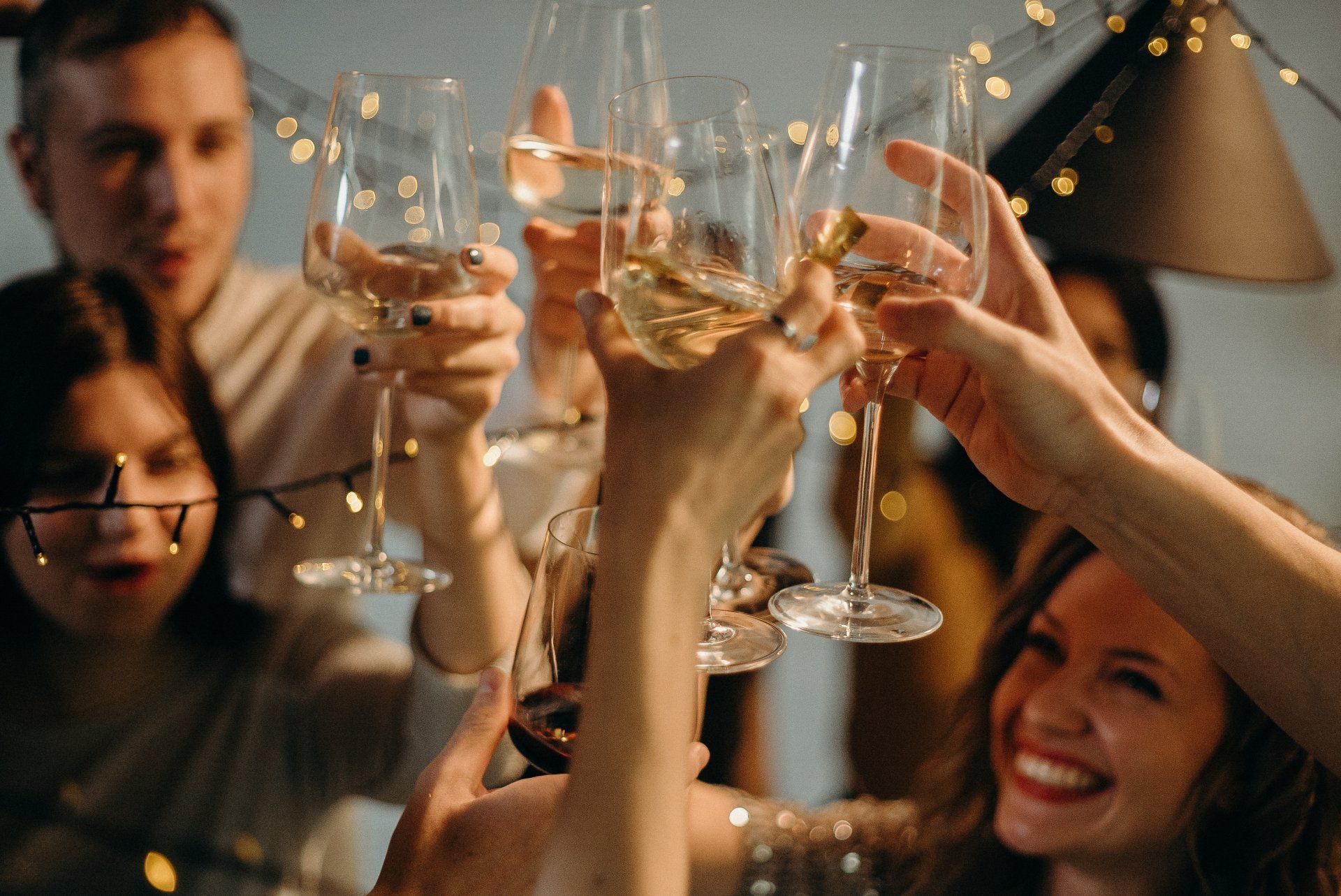 A group of people are toasting with wine glasses at a party.