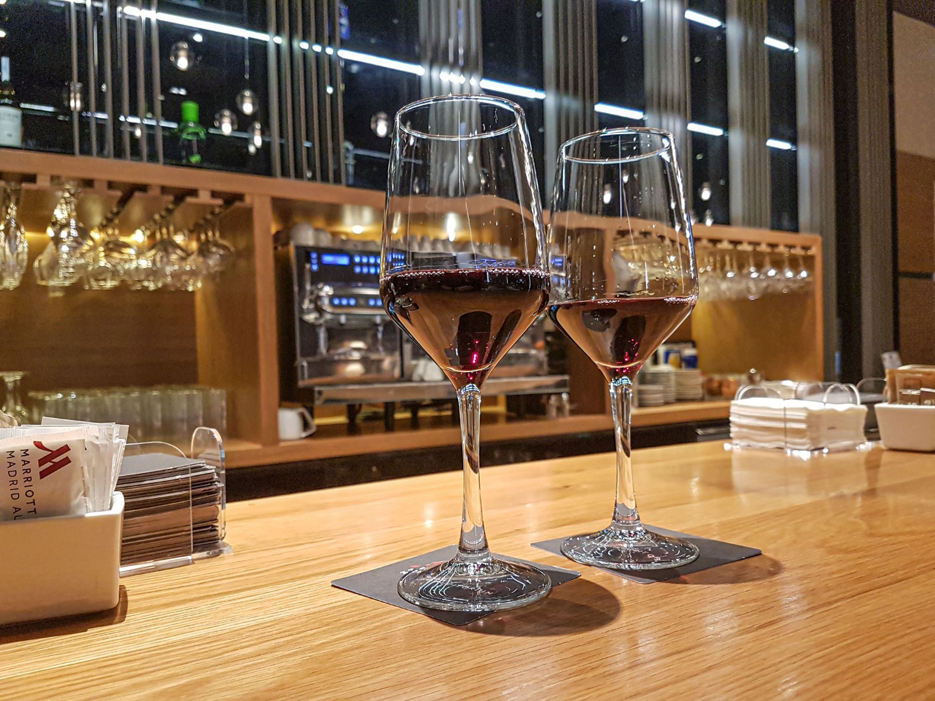Two glasses of wine are sitting on a wooden bar.