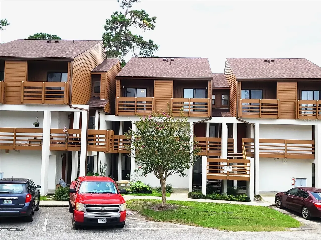 Brown and white townhouses with balconies and parking in front.