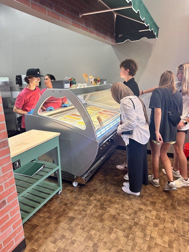 A group of people are standing in line at an ice cream shop.