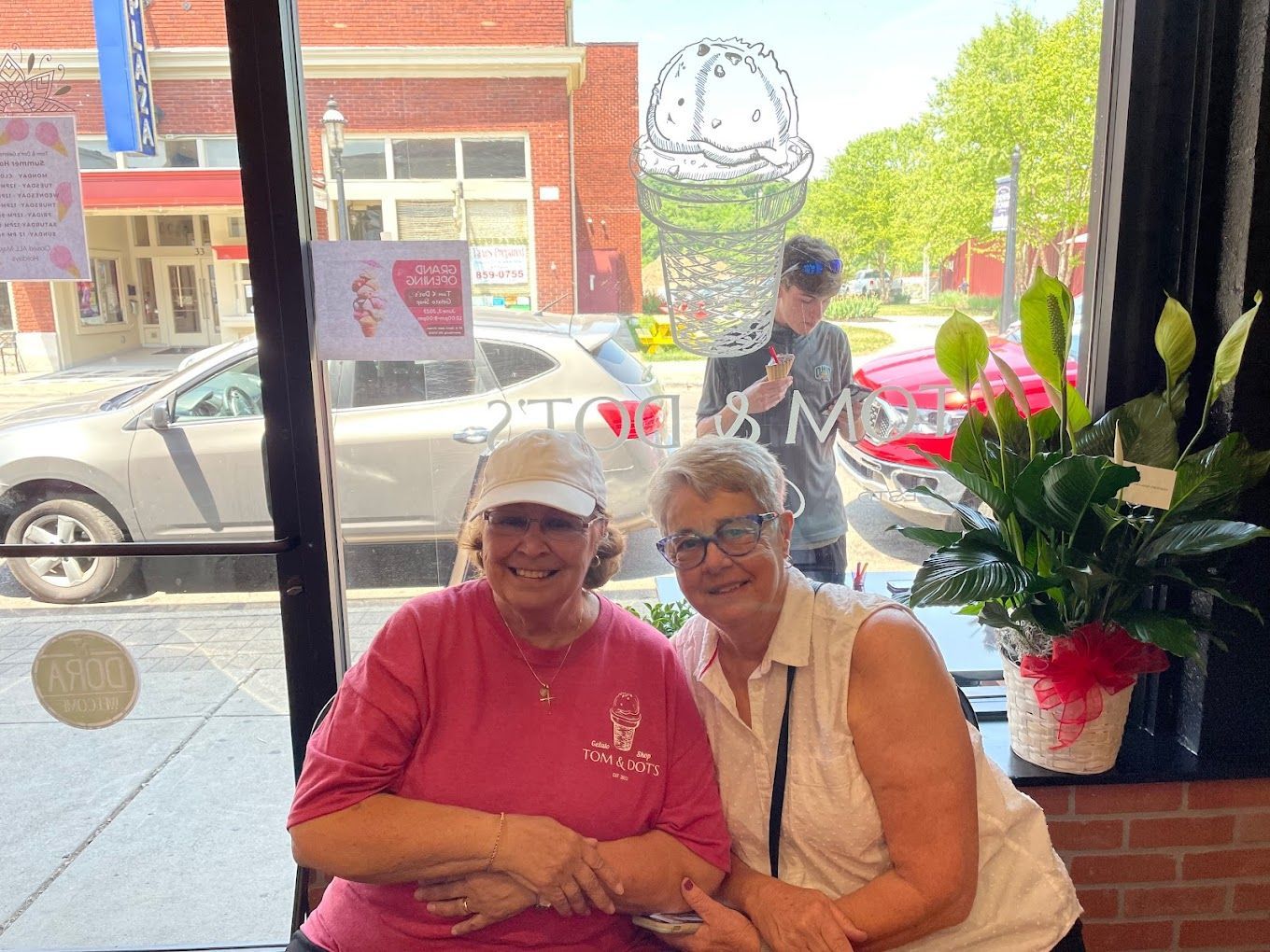 Two women are posing for a picture in front of a window.