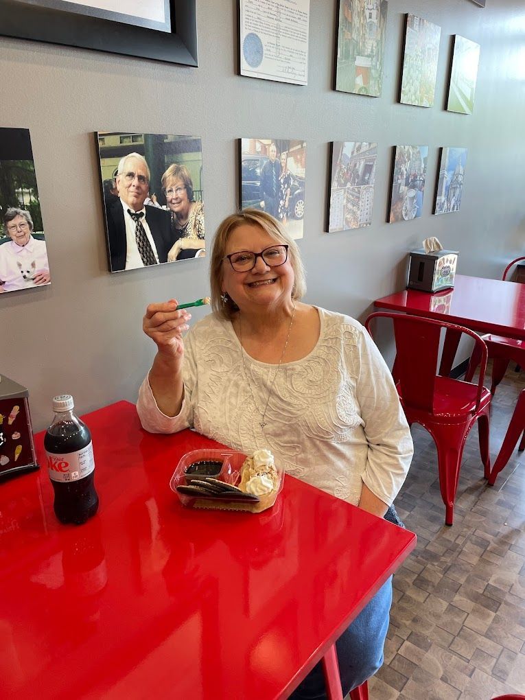 A woman is sitting at a red table in a restaurant eating food.