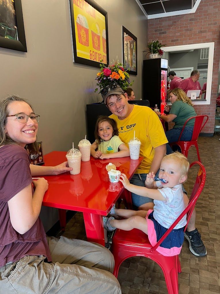 A family is sitting at a table in a restaurant eating ice cream.