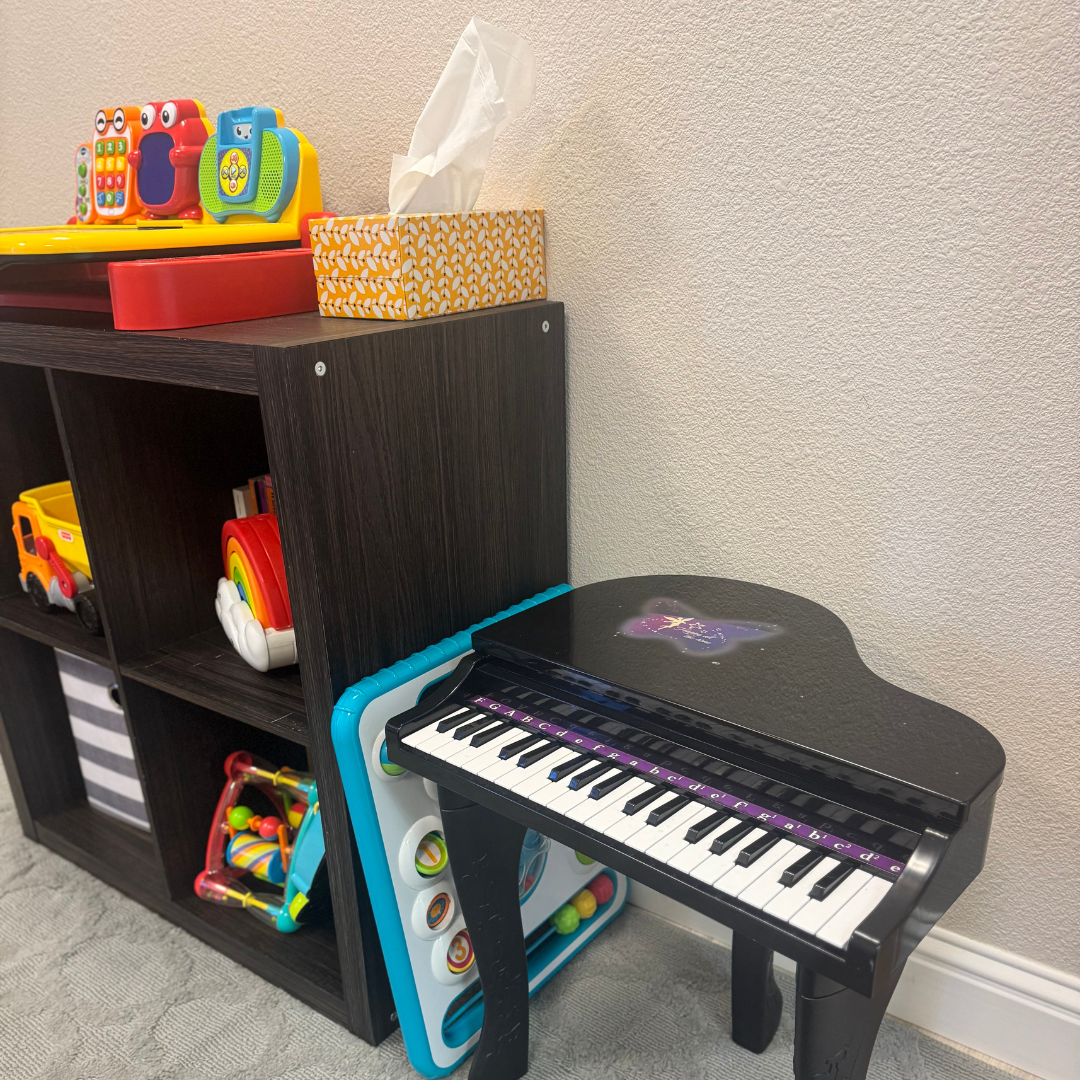 A piano is sitting next to a shelf with toys on it.