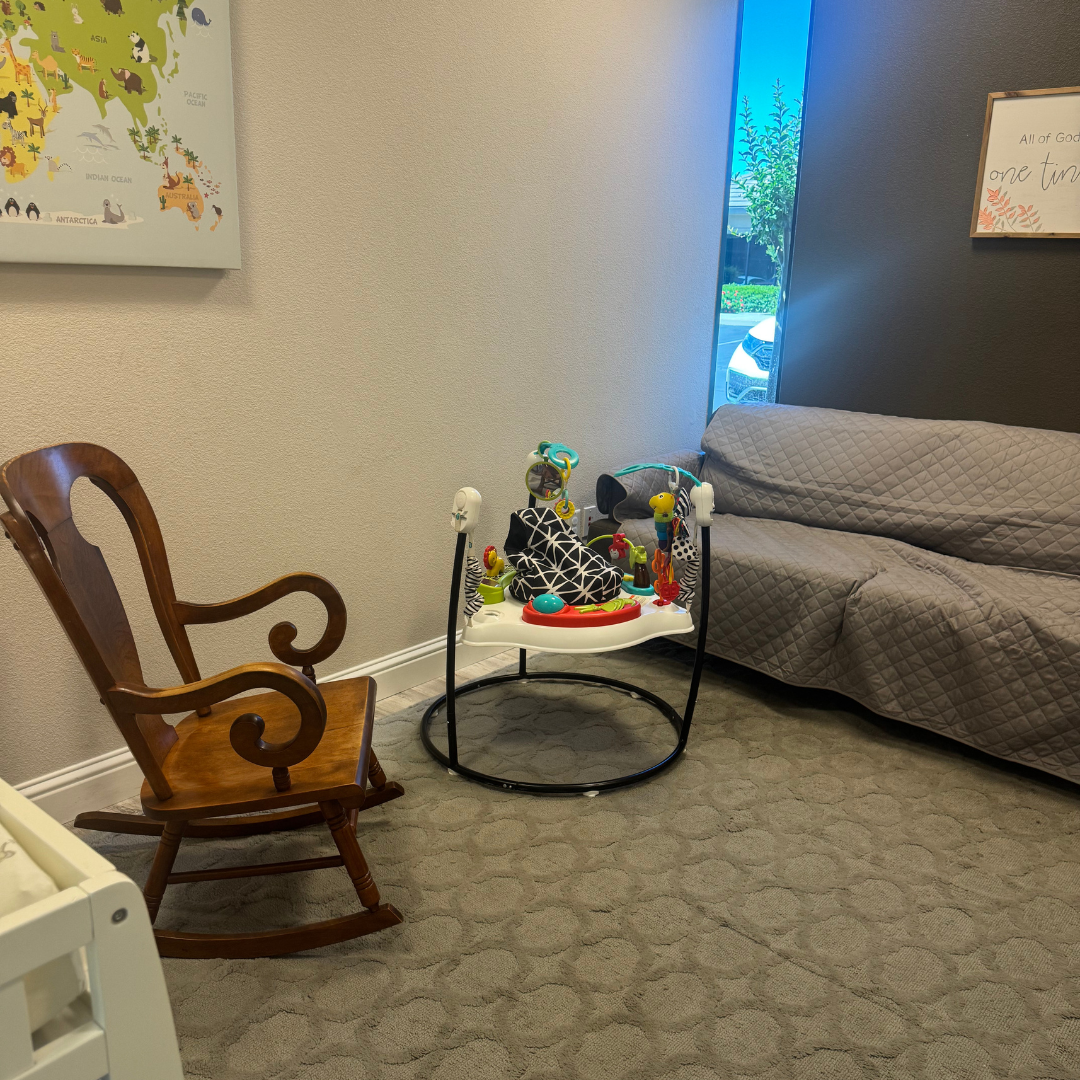 A room with a rocking chair a couch and a baby walker