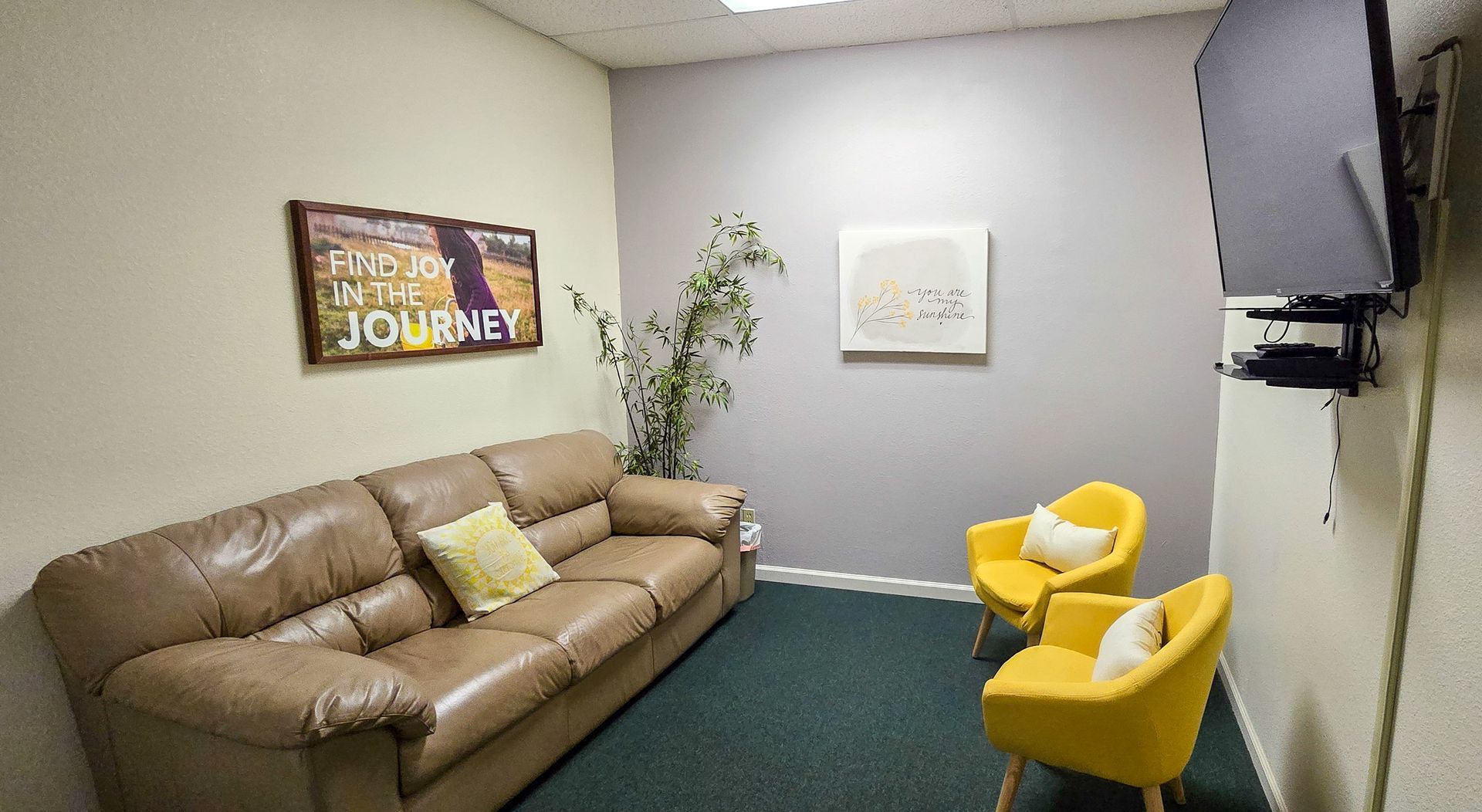 A television room with a comfortable couch and yellow chairs