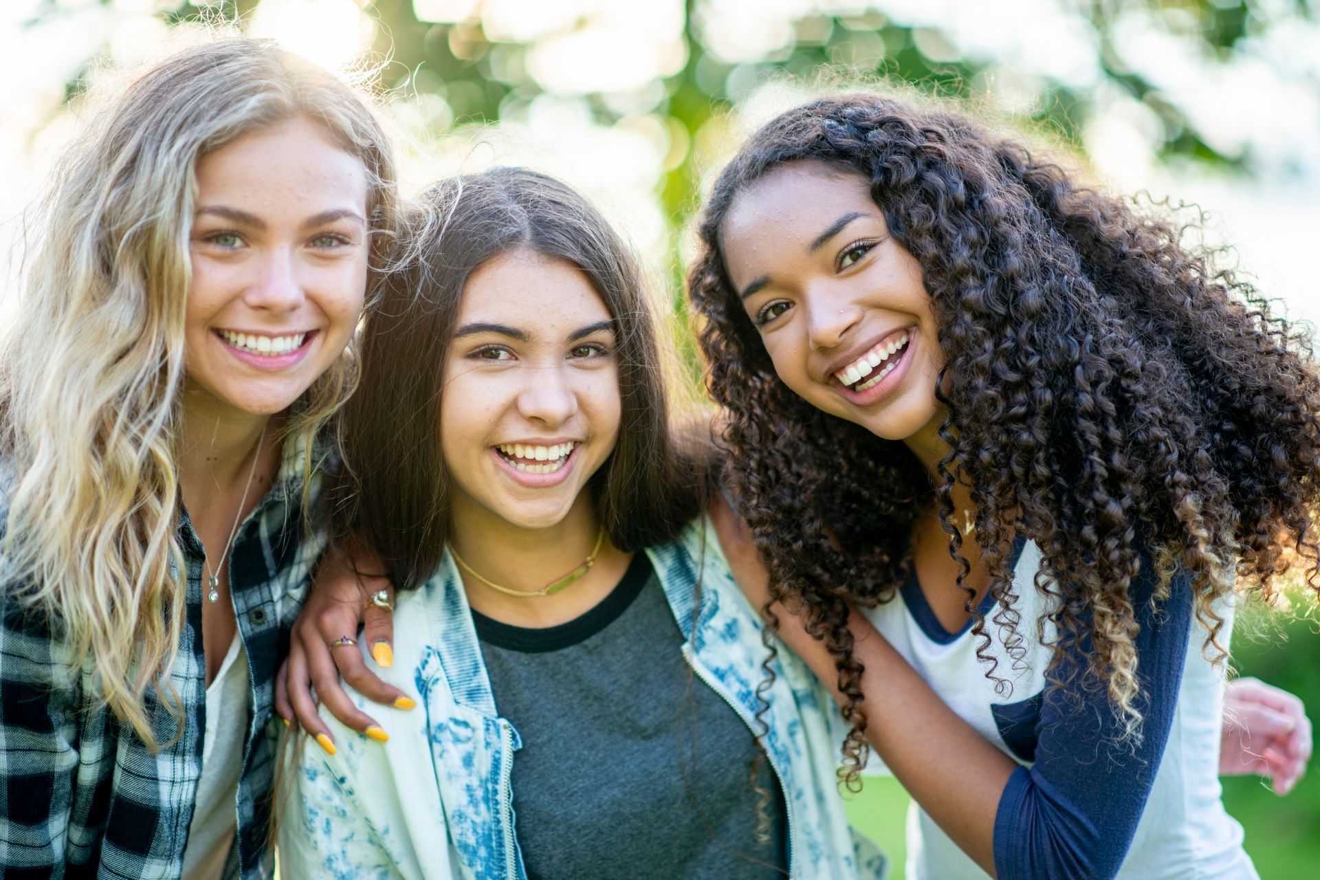 Three young women are posing for a picture together and smiling.