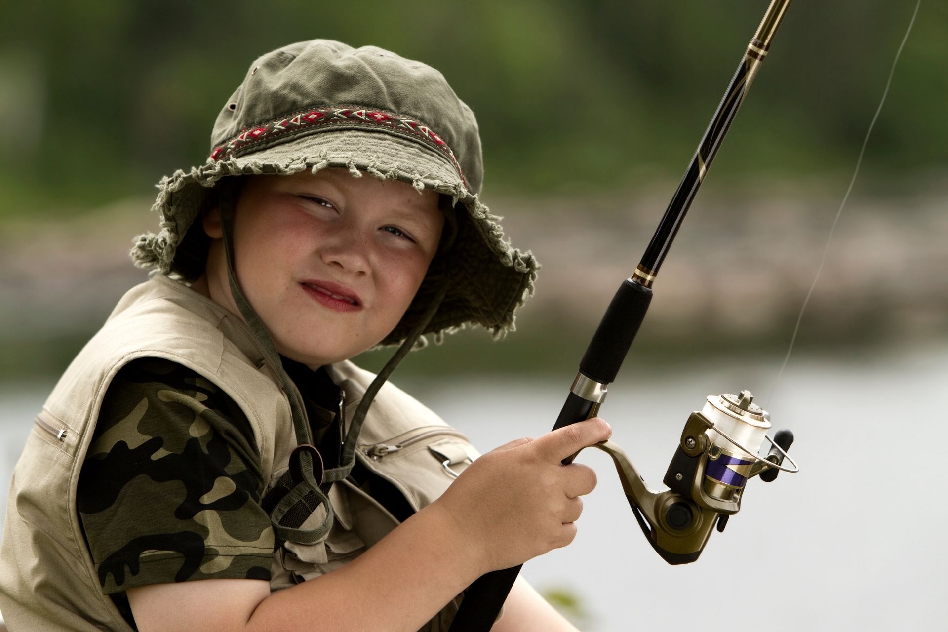 A young boy in a hat is holding a fishing rod