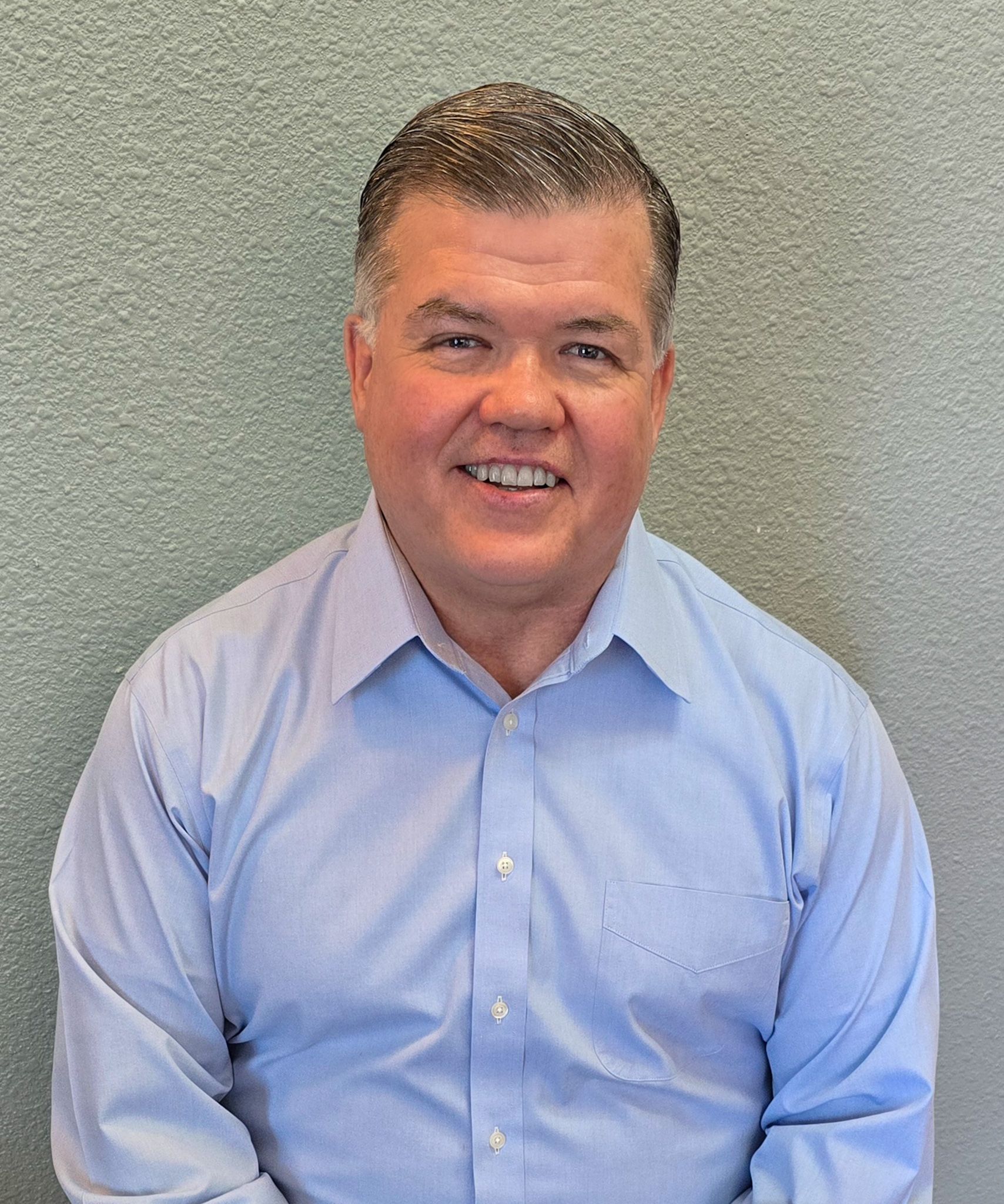 A man in a blue shirt is smiling for the camera.