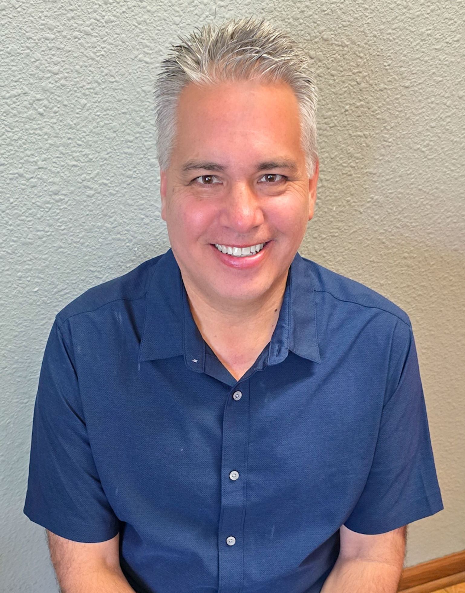 A man in a blue shirt is smiling for the camera.