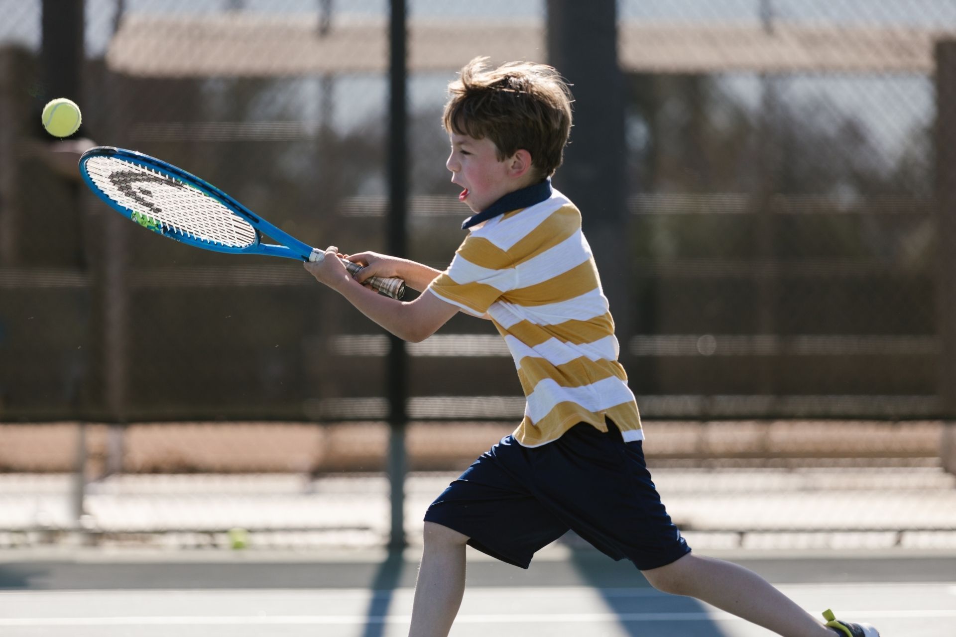A young boy is swinging a tennis racquet at a tennis ball.