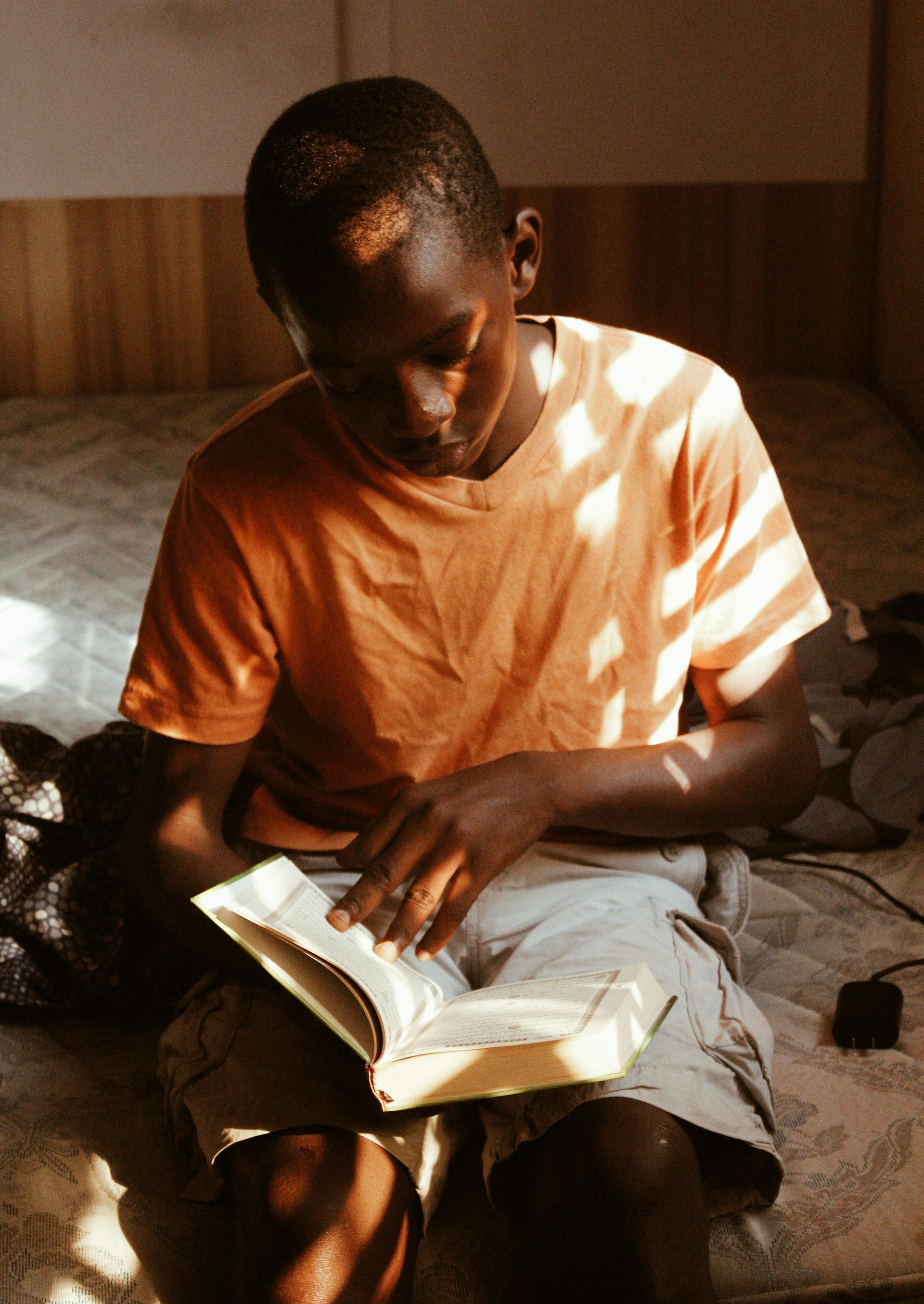 A man is sitting on the floor reading a book