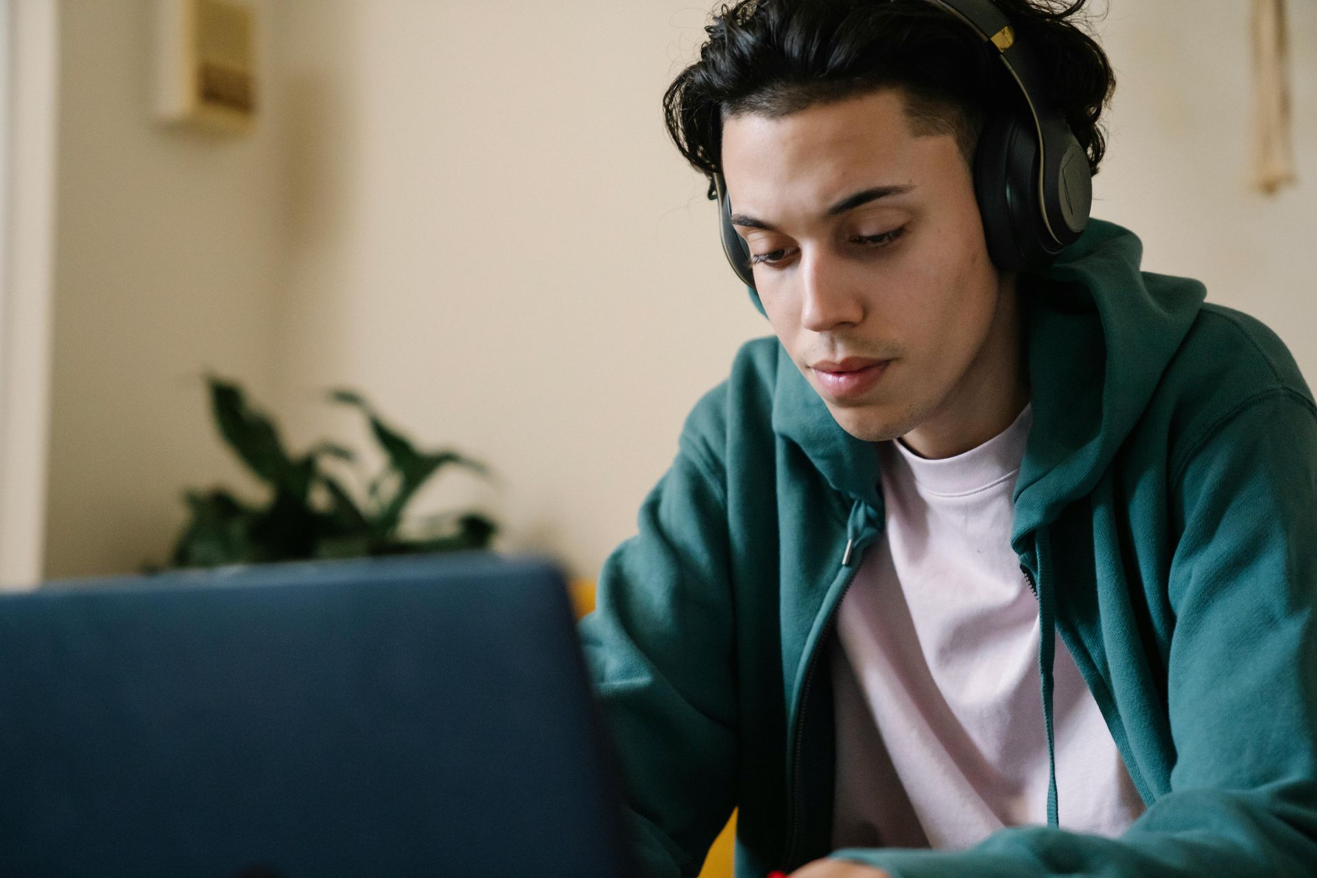 A young man wearing headphones is using a laptop computer.