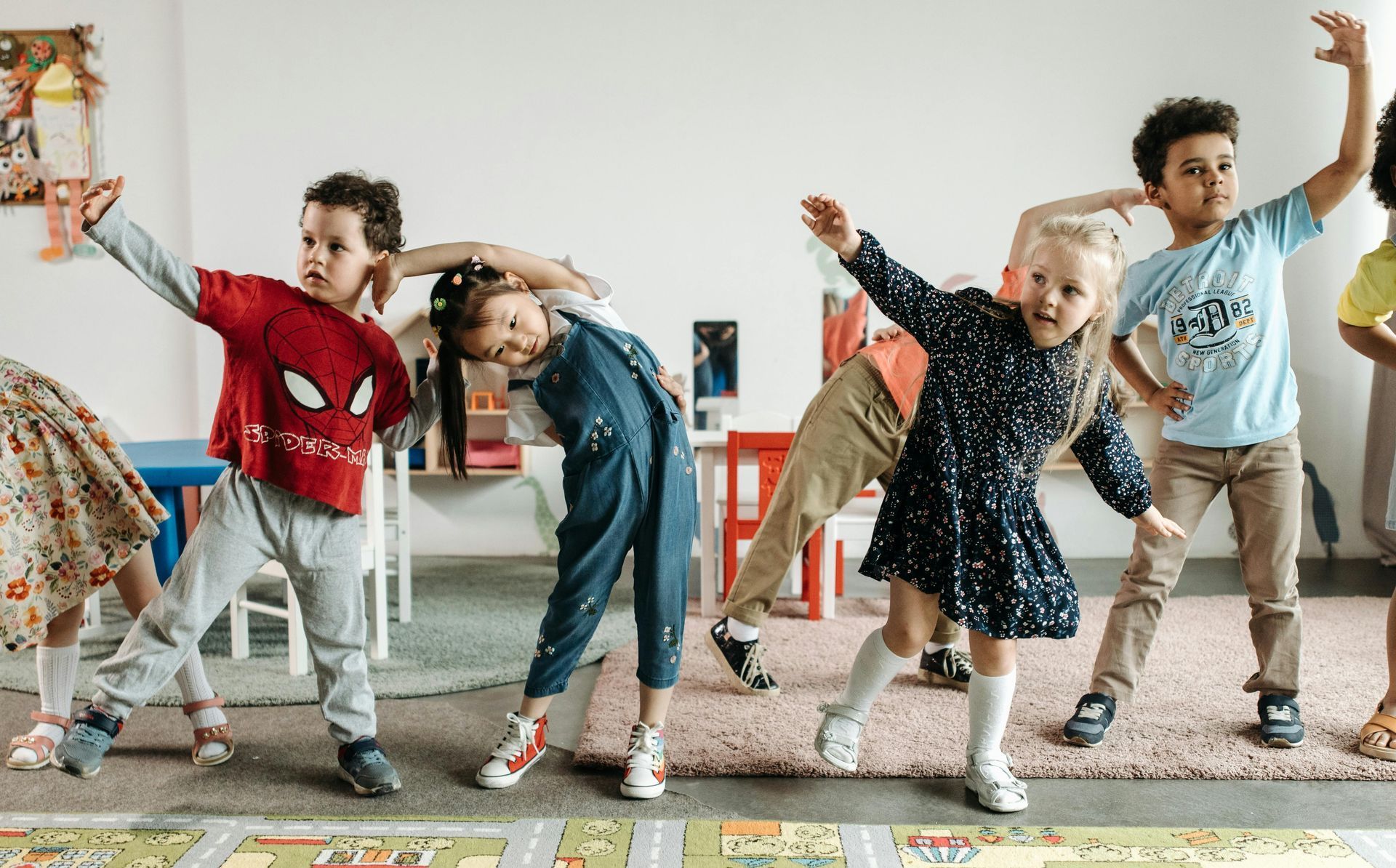 A group of children are dancing together in a classroom.
