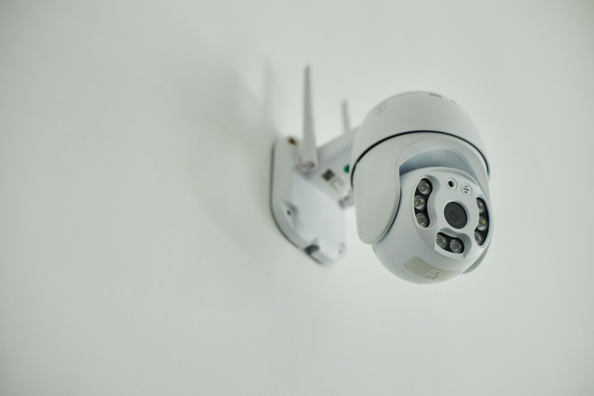 White security camera mounted on a white wall.