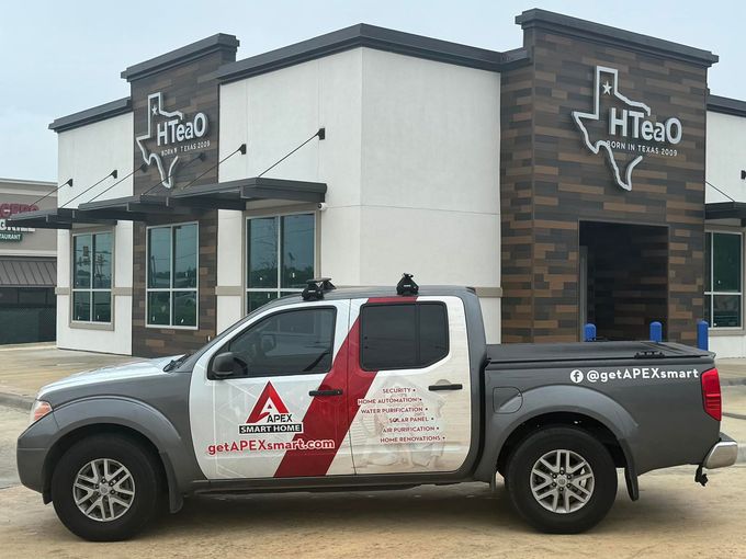 A gray pickup truck parked in front of an HTeaO building with a Texas-shaped logo.