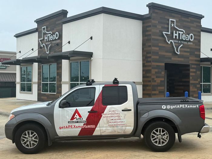 A gray pickup truck parked in front of an HTeaO building with a Texas-shaped logo.