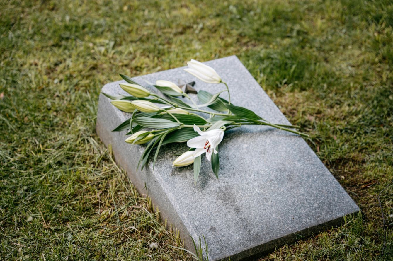 graveside memorial with white lilies resting on a stone grave marker in el cenizo, tx