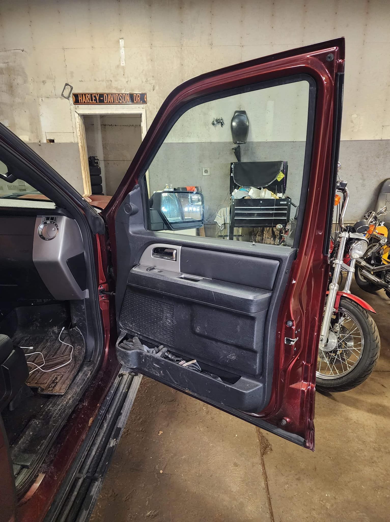 Open red truck door in a garage, revealing interior and motorcycle.