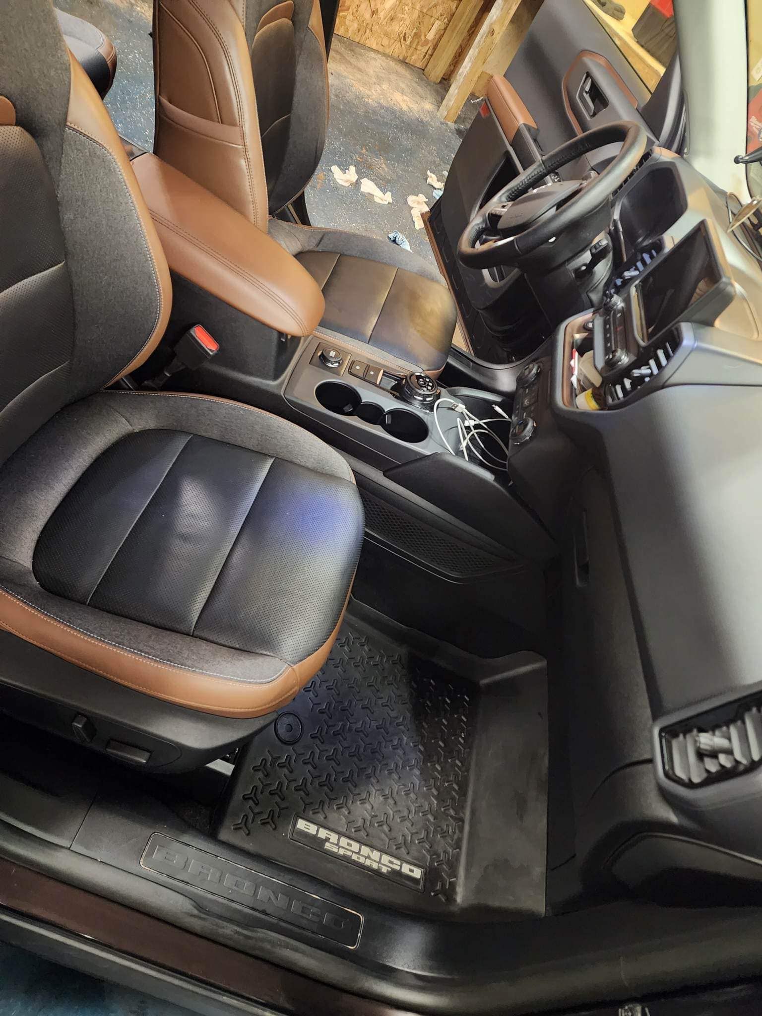 Interior of a vehicle with black and tan seats, steering wheel, and dashboard.