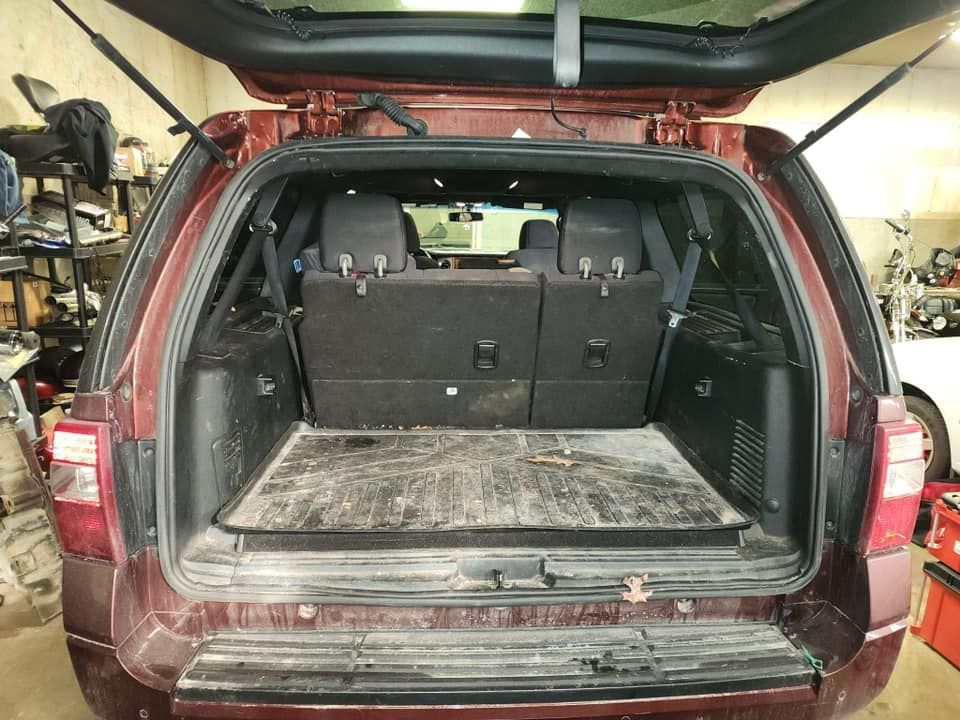 Back view of a maroon SUV trunk, open, showing the interior and folded-down seats.