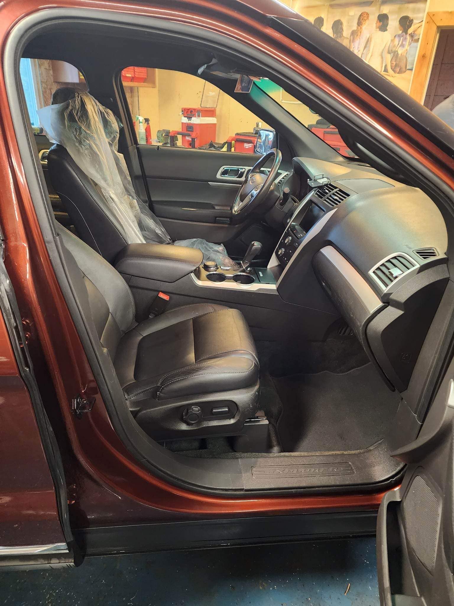 Interior of a brown SUV with dark leather seats and the driver's side door open.