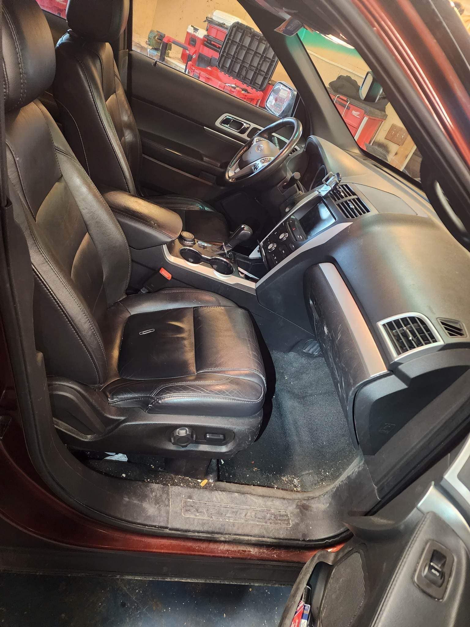Interior of a car with black leather seats, showing wear and debris.
