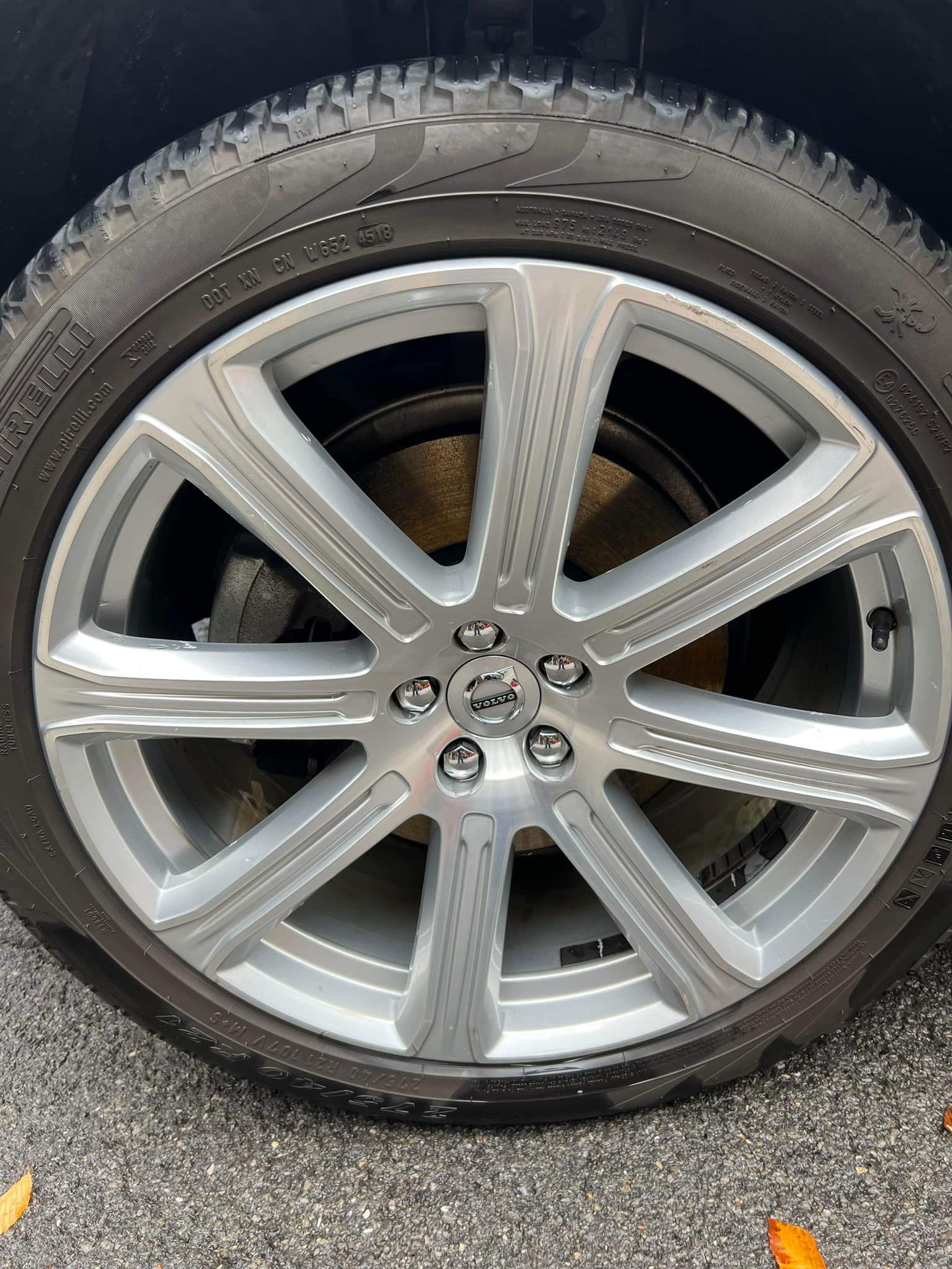 Silver car wheel with black tire on asphalt.
