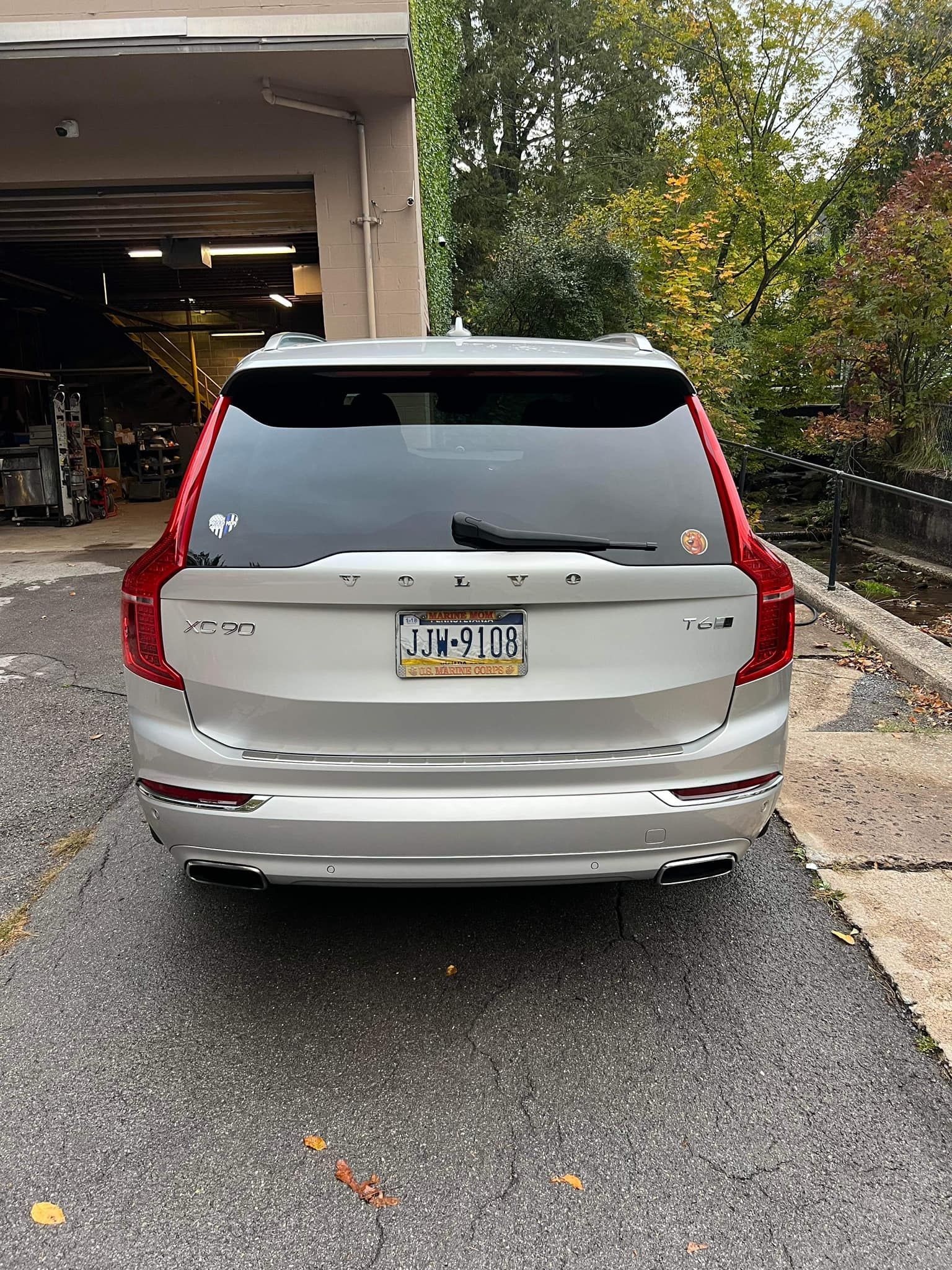 Silver Volvo XC90 SUV, rear view, parked on an asphalt driveway.