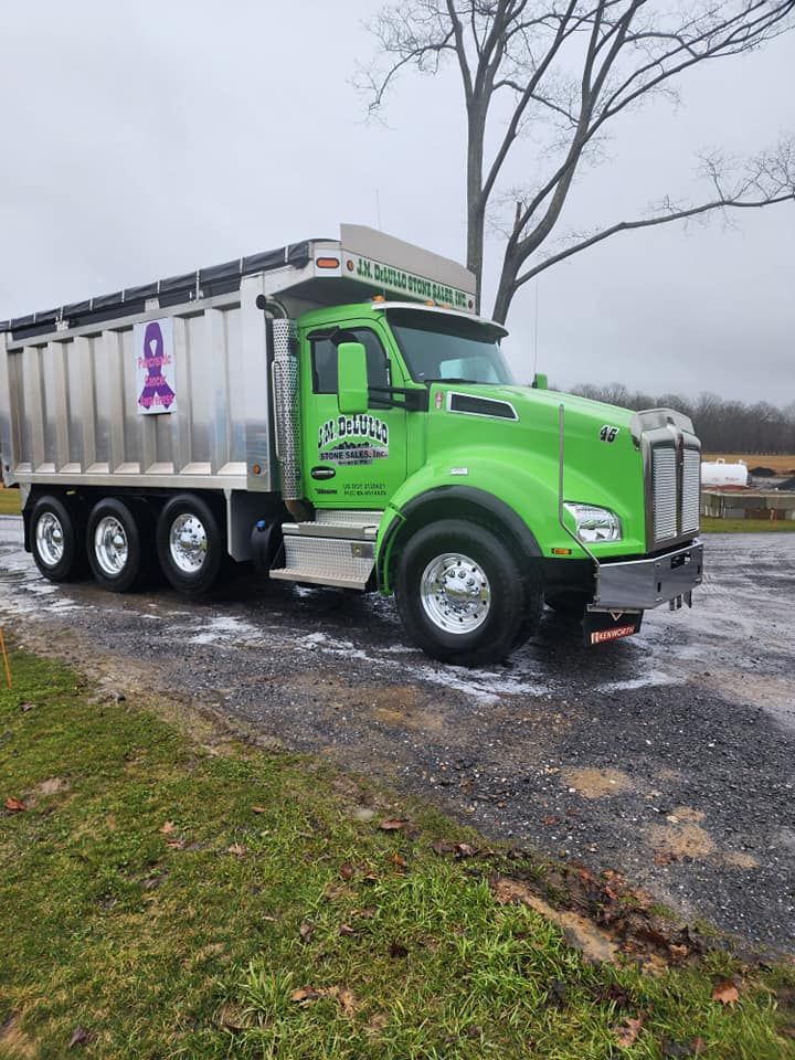 Bright green dump truck on a gravel drive, silver bed. 