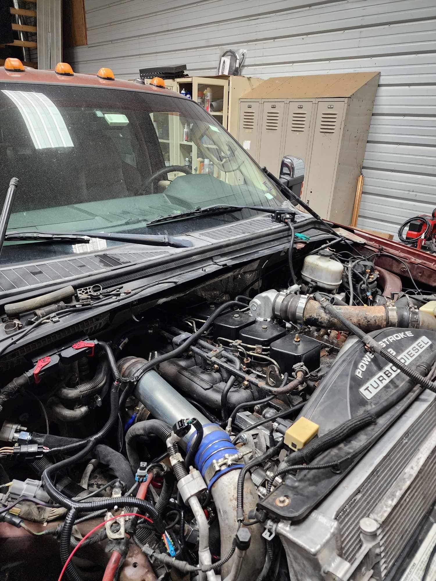 Open engine bay of a maroon pickup truck. Exposed engine with various components visible in a garage setting.