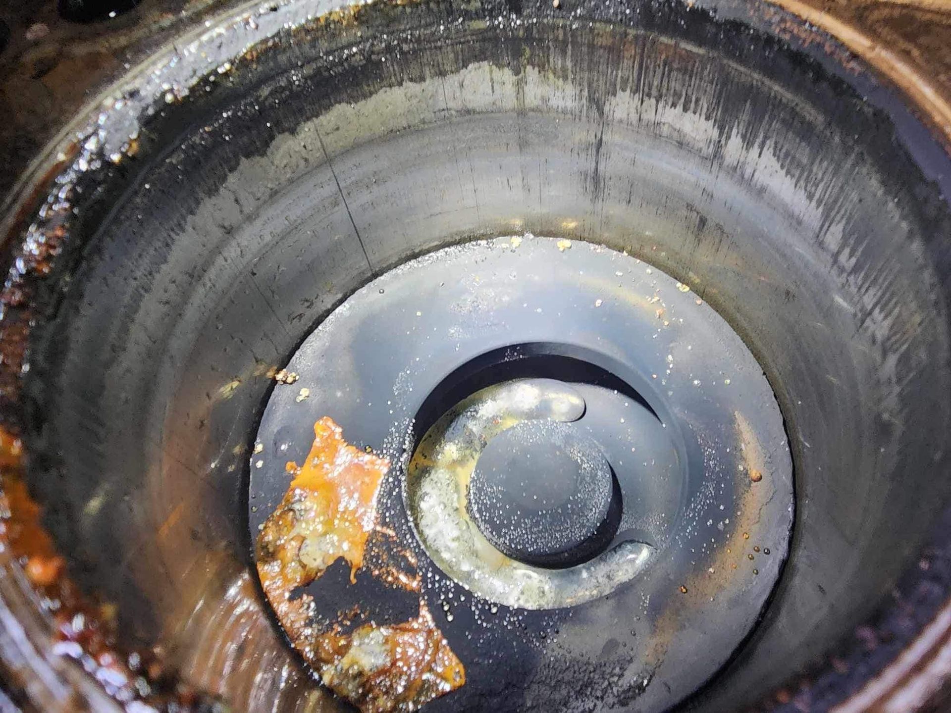 Cylinder bore with oil and debris at bottom, showing damage and wear.
